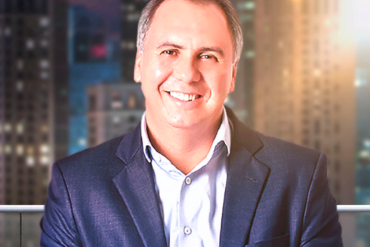 Marcos Trombettas ministrando o curso Conexão com a Riqueza, com elementos visuais de abundância e prosperidade.