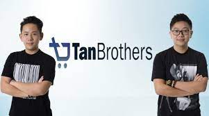 Tan Brothers: Imagem de dois irmãos sorrindo, um segurando um notebook e o outro um celular, com gráficos de crescimento ao fundo, representando sucesso em dropshipping.