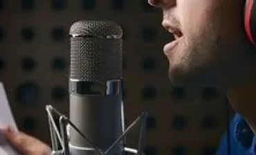 Mulher sorrindo cantando com microfone em estúdio profissional com luzes quentes.