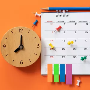 Homem focado organizando sua agenda com um laptop e materiais de estudo em uma mesa limpa, representando produtividade e gestão do tempo.