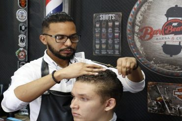 Homem confiante e estiloso em uma barbearia moderna com ferramentas de corte de cabelo e barba em foco.