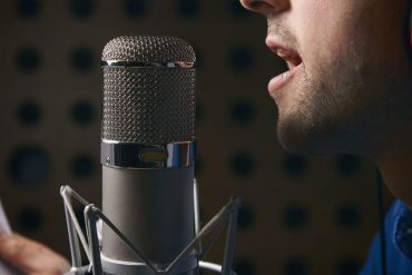 Estudante praticando canto com microfone em estúdio profissional, focando em técnica vocal com curso Andre Fantom.