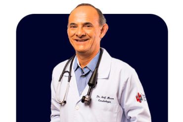 Homem médico experiente interpretando traçado de eletrocardiograma em tela, foco no detalhe do ECG