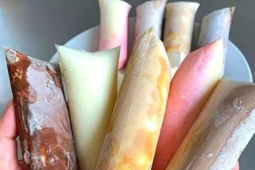 Mulher empreendedora feliz fazendo geladinhos gourmet com ingredientes coloridos e embalagens atraentes