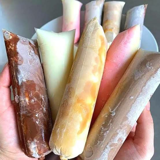 Mulher empreendedora feliz fazendo geladinhos gourmet com ingredientes coloridos e embalagens atraentes